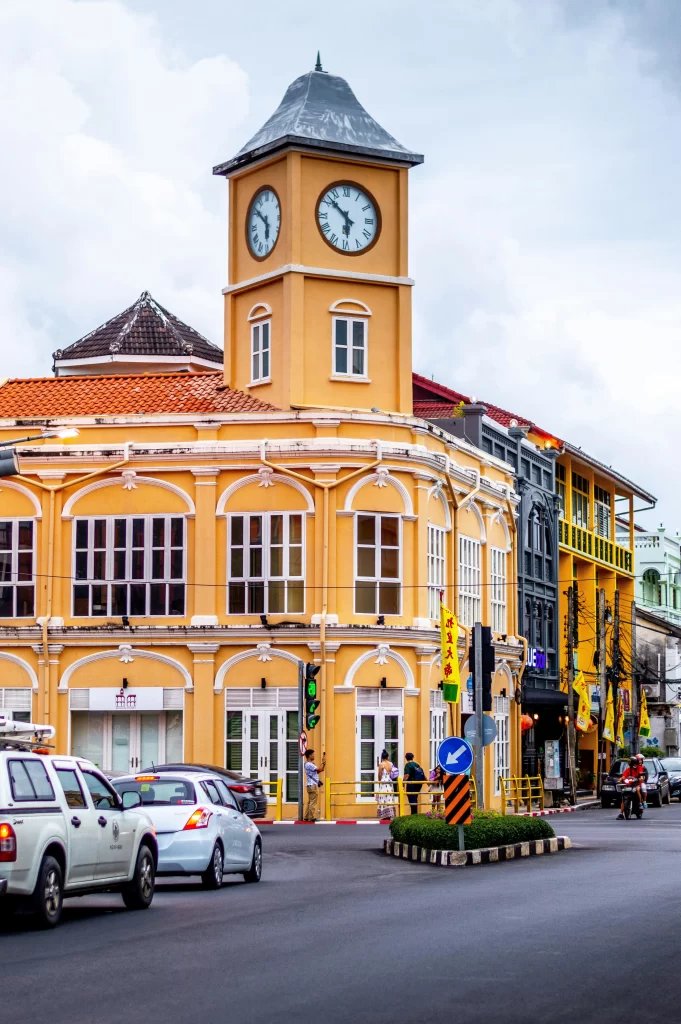 A cinematic photo of the vibrant, colorful Sino-Portuguese architecture along a sunlit street in Phuket Old Town, representing a family's cultural and culinary exploration.
